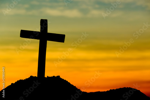 Concept conceptual yellow cross religion symbol silhouette in nature over sunset or sunrise sky