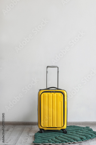 Bright yellow suitcase and leaf shaped rug indoors