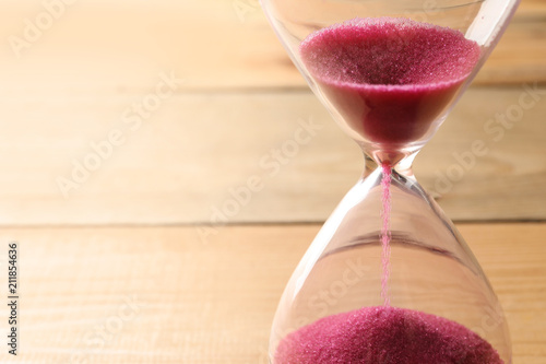 Hourglass with flowing sand on table, closeup. Time management