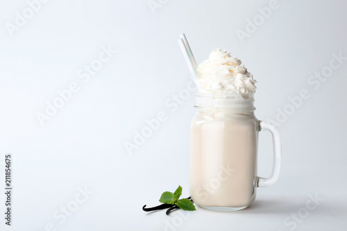 Mason jar with delicious milk shake on white background