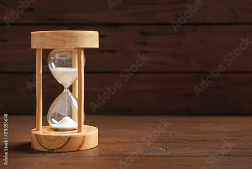 Hourglass with flowing sand on table against black background. Time management © New Africa