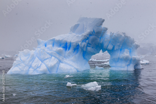 Blue iceberg arch in snowy weather, from sea level, Waterboat Point, Paradise Bay, Graham Land, Antarctic Peninsula, Antarctica photo