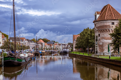 Canal view in a Dutch city with an old defence wall and tower just after rainfall