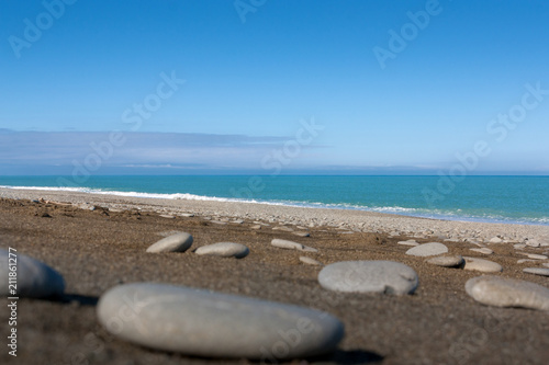 Stones and pebbles up close on a gravel beach with a turquoise sea