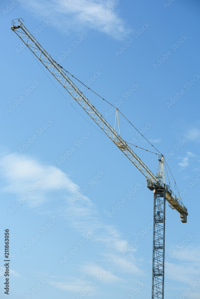 Tall construction crane against blue sky Tall construction crane against blue sky