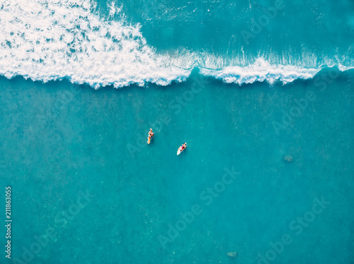Canvas Print Aerial view of surfers and wave in tropical ocean. Top view