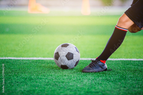 The soccer player shoot ball on artificial turf.