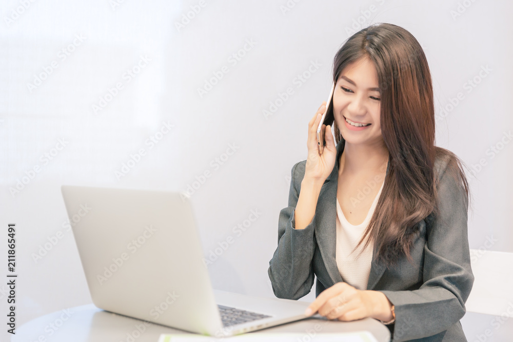 Business woman talking smart phone to customer in modern office with computer laptop for background. Business woman talking smart phone to customer in modern office with computer laptop for background.