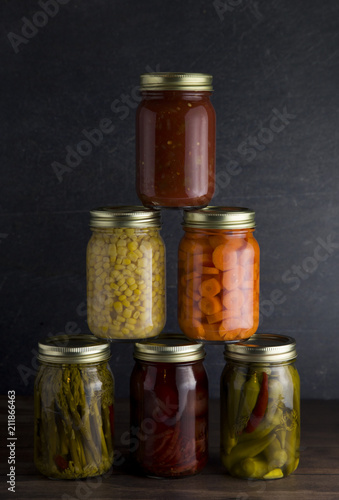Various Types of Canned Vegetables on a Wooden Table in a Dark Environment