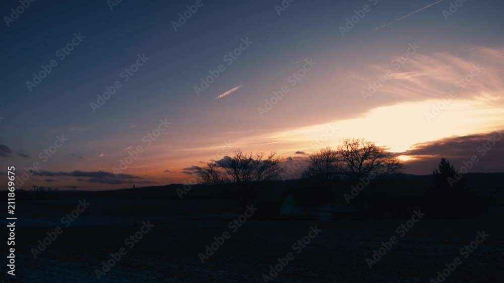 Wide shot of a cinematic purple sunset with backlight trees in the foreground. Wide shot of a cinematic purple sunset with backlight trees in the foreground.