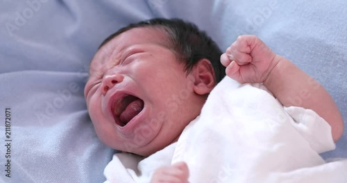 New born baby crying on bed photo