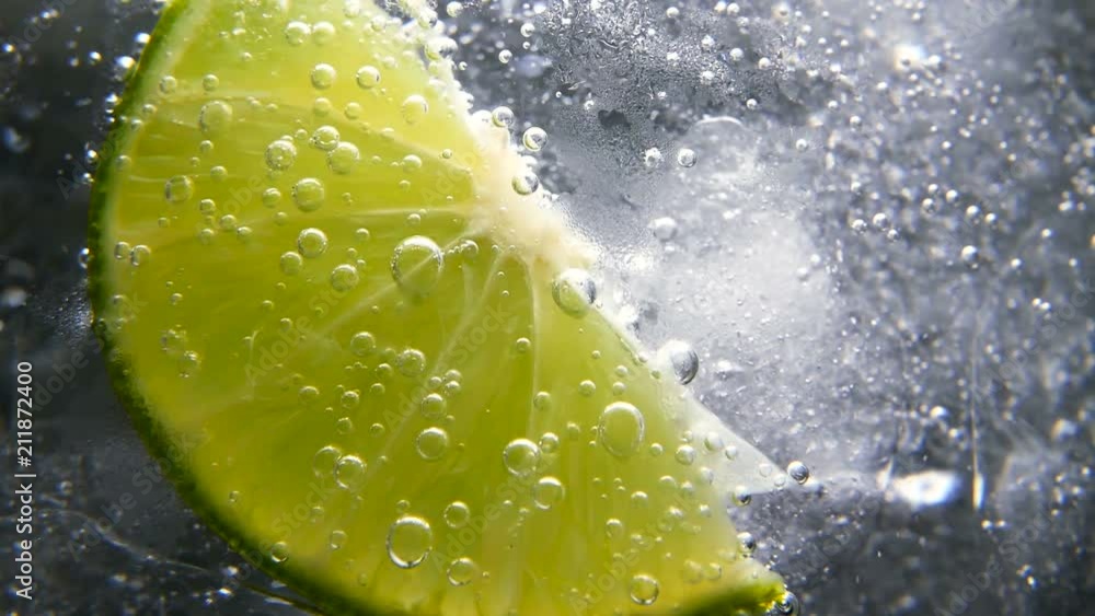 Macro close-up,refreshing soda tonic fizzy water, lime in Glass, ice. Slice of lemon, mineral bubbles. Detox or thirst concept. Healthy, dietary nutrition. Cold lemonade mojito drink. Black background