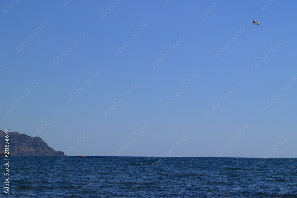 Image of the sea shore. A water motorcycle tows a parachutist. Image of the sea shore. A water motorcycle tows a parachutist.