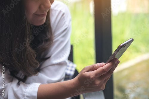 Free Download Closeup image of an asian woman holding , using and looking at smart phone - GFXLoad