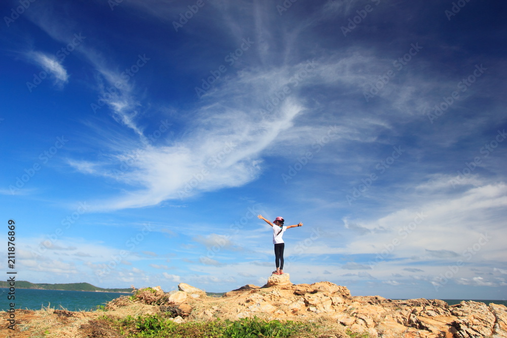 Child girl with arms wide open enjoying the sea,Stand on rock with hand up feel relax or happy or freedom travel,Success and winner concept. 