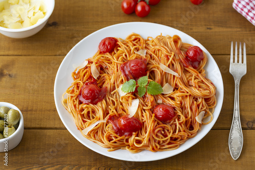 spaghetti with tomato sauce in the dish on the wooden table