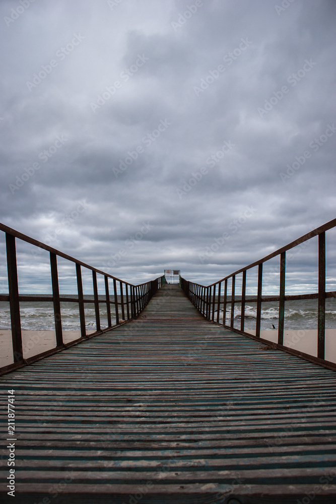 Wooden pier at sea. Gloomy weather.