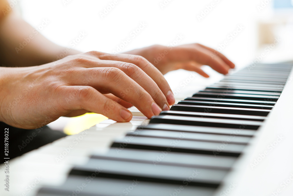 Fototapeta premium Close up of pianists hand playing piano. Shallow deep of field.