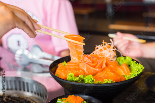 Raws salmon fillet with chopsticks on dish in restaurant