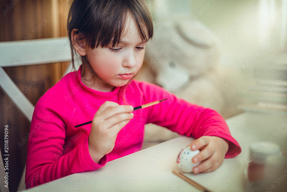 Girl painting on the easter egg at the desk Girl painting on the easter egg at the desk