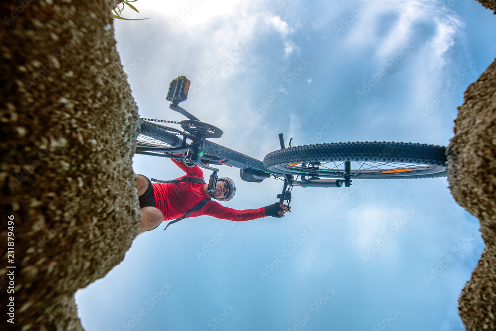 bottom view of cylist with mountain bike try to step over the obstacle during the way of riding