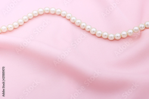 Pearl necklace on the pink fabric with copy space.