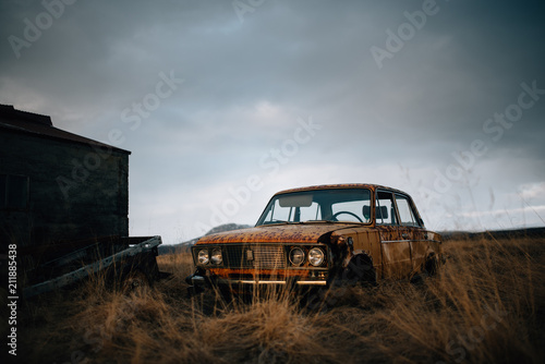 Broken car in the field at sunset
