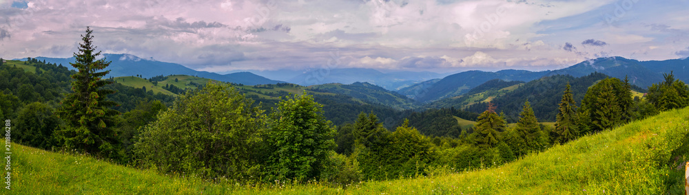 A picturesque view of the vast endless green Carpathian mountains against the blue sky with white clouds