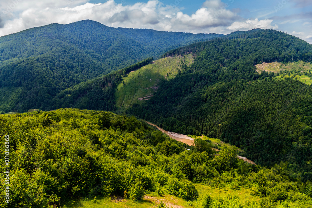 Fototapeta premium Krajobraz przedstawiający doliny, zagłębienia i wspinaczki na ogromnym zielonym paśmie górskim