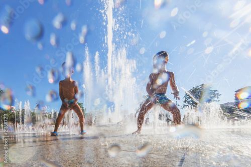 Unidentified Kids playing in the fountain in city park © epic_images