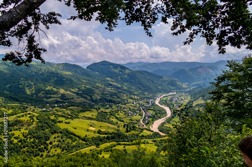 A small and very picturesque village on green mountain meadows under a cloudy sky