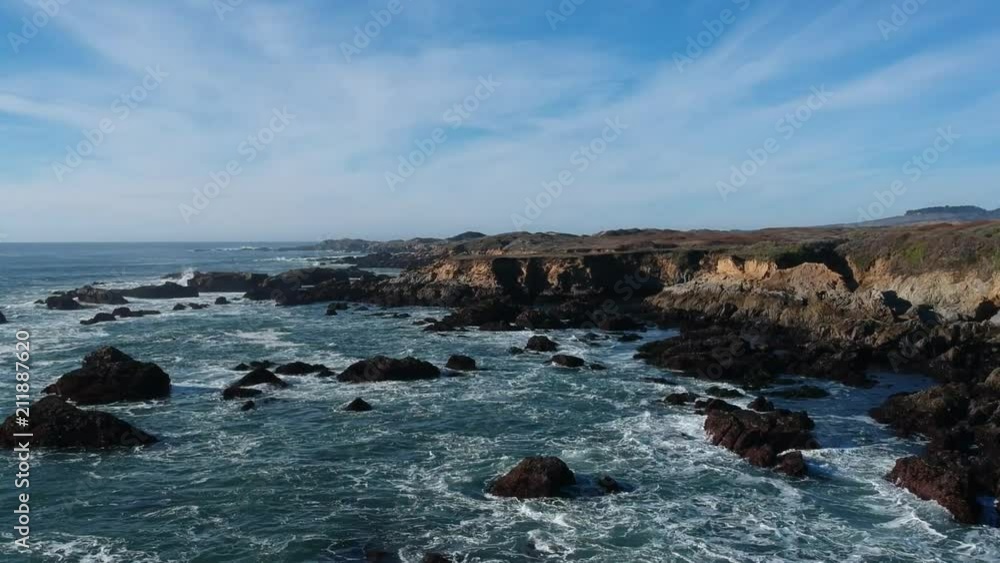 Half-circling aerial shot of waves breaking over rocky shore Half-circling aerial shot of waves breaking over rocky shore