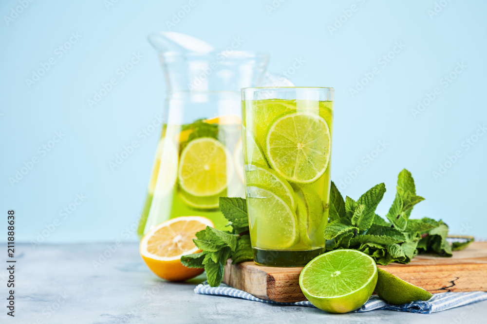 Yellow and green cocktail with lime, lemon and mint close-up view. Blue background. Copy space for text.