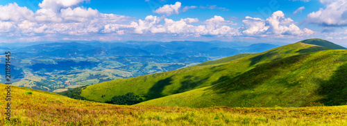 bright peaks of the Carpathians are covered with green grass  over which white fluffy clouds swim