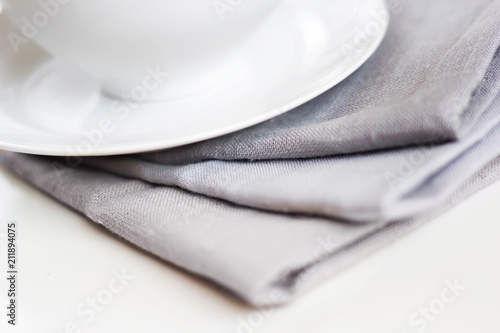 Empty white plate and bowl on a stack of gray napkins on a table.