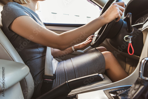 cropped image of businesswoman in grey dress driving auto