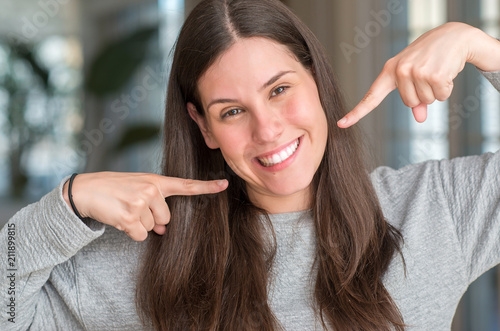 Young beautiful woman at home smiling confident showing and pointing with fingers teeth and mouth. Health concept.