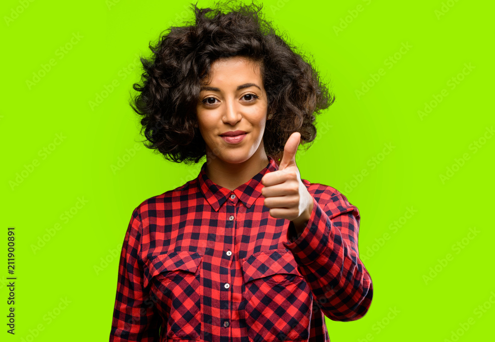 Beautiful arab woman smiling broadly showing thumbs up gesture to camera, expression of like and approval Beautiful arab woman smiling broadly showing thumbs up gesture to camera, expression of like and approval