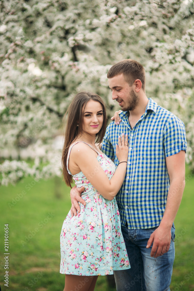 Young couple in love resting in the blooming garden. white blooming trees Young couple in love resting in the blooming garden. white blooming trees