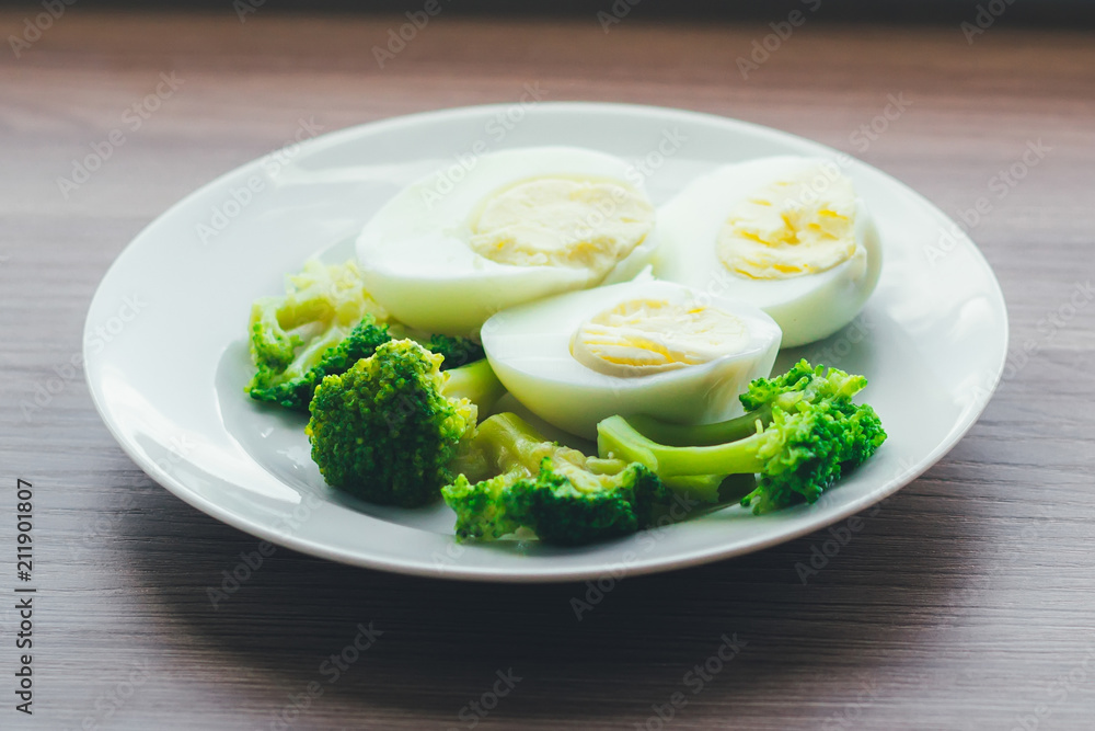 Boiled eggs and broccoli on a white plate on a wooden table. Boiled eggs and broccoli on a white plate on a wooden table.