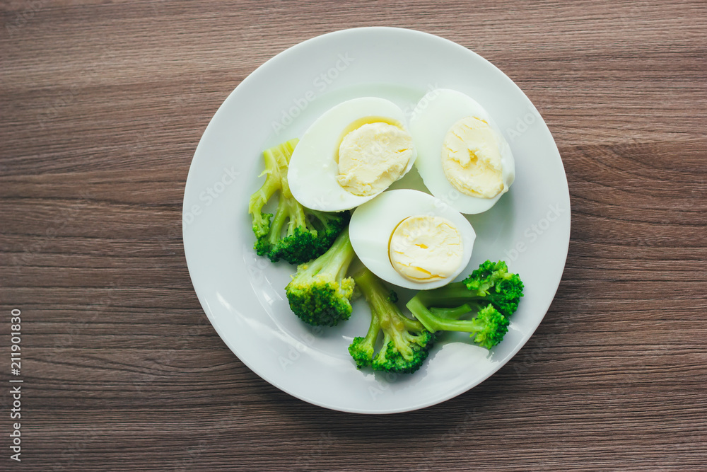 Boiled eggs and broccoli on a white plate on a wooden table. Boiled eggs and broccoli on a white plate on a wooden table.