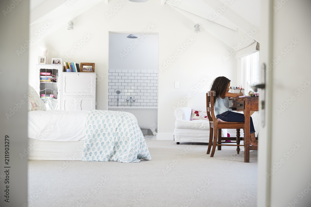 Young black girl sitting at desk, doing homework in her room Young black girl sitting at desk, doing homework in her room