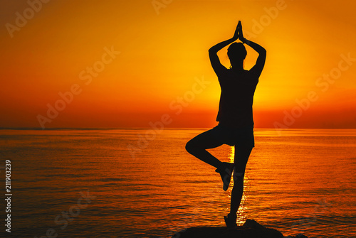 Silhouette of a girl in a yoga pose at sunset