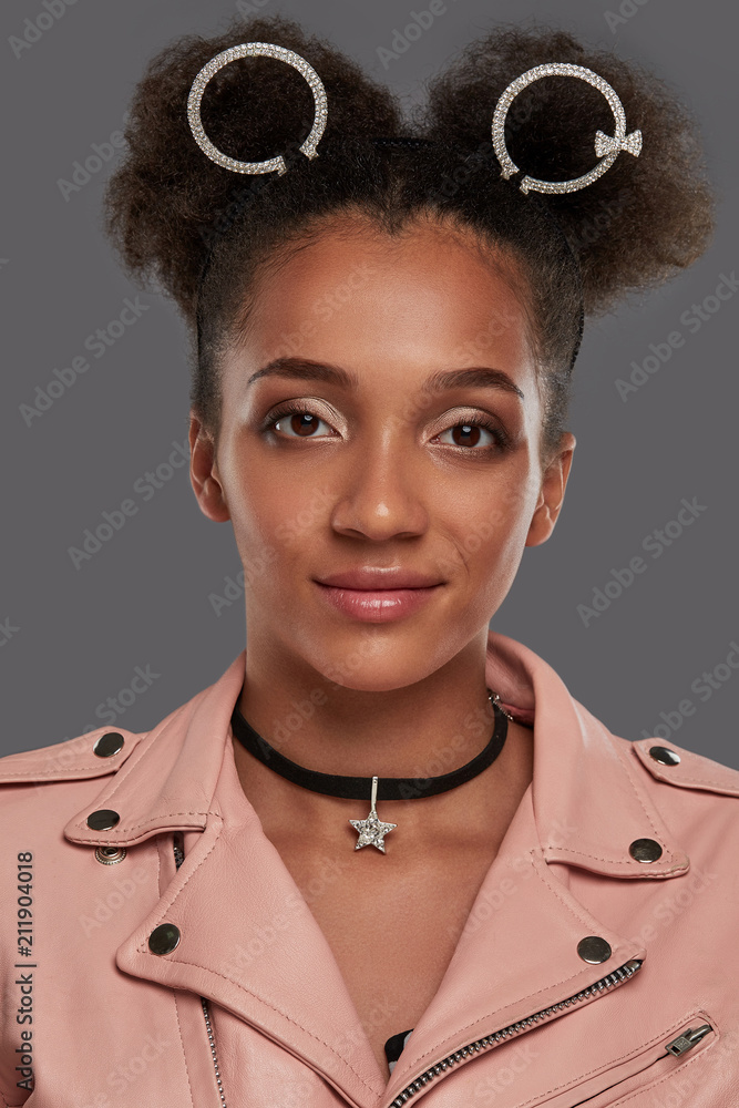 A close up portrait of a young African lady in a pink biker jacket, with  curly