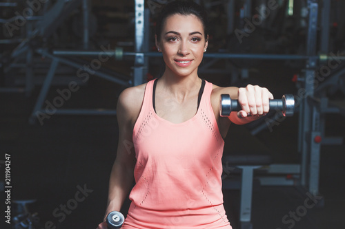 Sporty young woman makes sport exercises in the gym