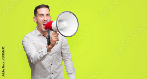 Handsome young man holding microphone annoyed and frustrated shouting with anger, crazy and yelling with raised hand, anger concept