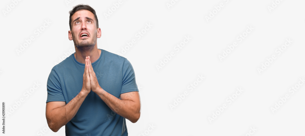 Handsome young casual man begging and praying with hands together with hope expression on face very emotional and worried. Asking for forgiveness. Religion concept. Handsome young casual man begging and praying with hands together with hope expression on face very emotional and worried. Asking for forgiveness. Religion concept.