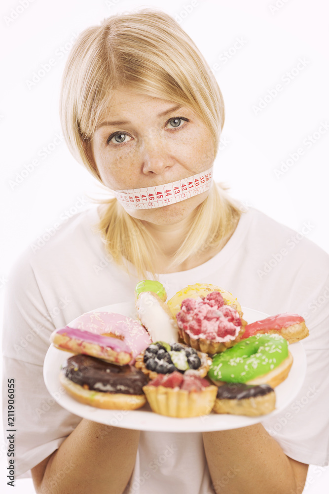 Young woman on a diet with a plate with cakes, isolated on white background
