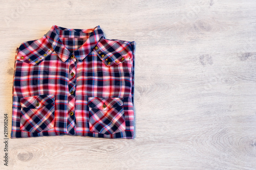 Multi-colored checkered women's shirt lying neatly folded on a l