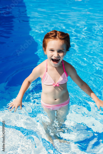 laughing little child in bikini in swimming pool